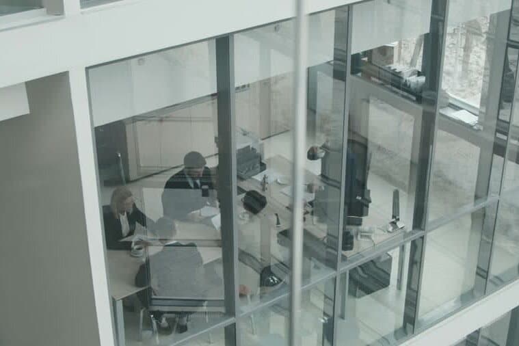 Colleagues meeting at a desk inside a glass-walled office